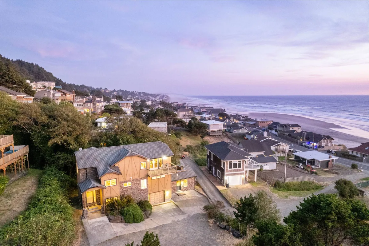 This image offers a sweeping view of the showcased property nestled within the surrounding coastal town, with the beach and ocean stretching out beyond. The vantage point highlights both the inviting town atmosphere and the home's proximity to the shoreline, encapsulating the sense of arrival and exploration.